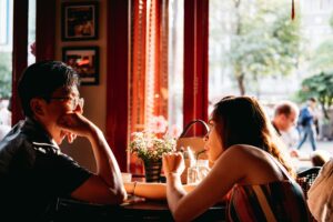 Couple having an engaging, authentic conversation at a coffee shop, showing how real connection happens through being genuinely interesting rather than using pickup lines